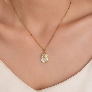Detailed close-up of a golden tulip pendant with white enamel on a beaded chain necklace