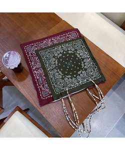 Detail of paisley print tote bags with multi-colored beaded handles on wood table
