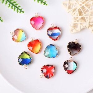 Colorful glass heart pendants with gold frames in a white ceramic dish for DIY jewelry