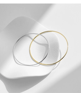 Minimalist gold and silver bangle bracelets displayed on a ceramic tray closeup