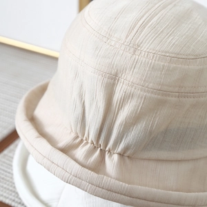 Minimalist beige bucket hat with pleated texture fabric and rounded crown structure