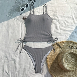 Flat lay of black and white striped two-piece swimsuit with side drawstring detail