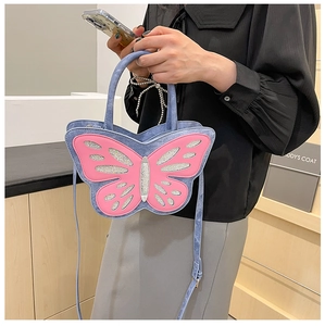 Detail of denim butterfly handbag featuring pink glitter applique and adjustable strap