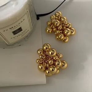 Detail of gold cluster ball stud earrings with polished metallic spheres on a jewelry card
