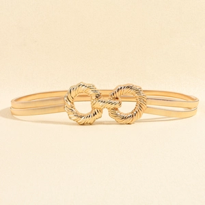 Close-up of golden elastic spring waist chain with double ring buckle on beige background