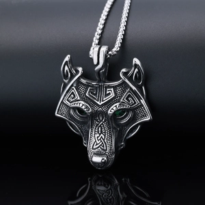 Macro view of a punk wolf head pendant in antique silver with green gemstone eyes