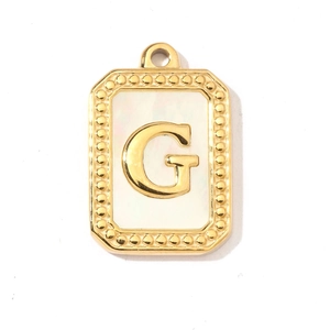 Detailed view of rectangular shell pendant with golden bead edge and letter G engraving