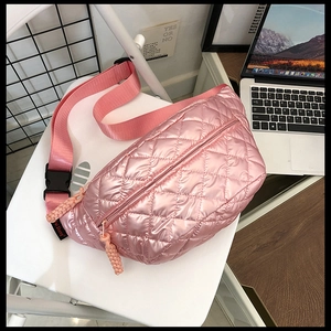 Detailed close-up of a pink quilted crossbody bag with diamond patterns and a wide strap