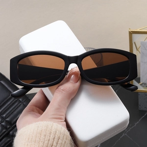 Close-up of stylish black rectangular sunglasses with brown lenses on a sleek white case
