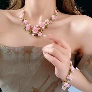 Détail des roses en résine rose et perles du collier porté par un mannequin féminin