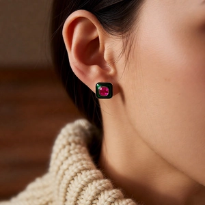 Detail of vintage square emerald enamel earrings with red gemstone inlay on model
