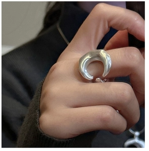Detailed view of an oversized matte silver crescent open ring worn on a finger