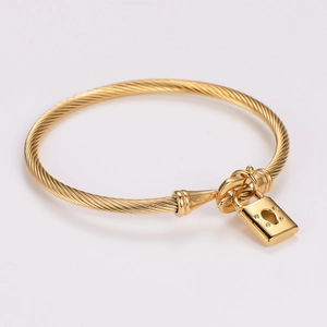 Detailed close-up of golden stainless steel twisted cable bracelet with a lock charm