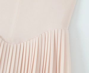Detail of the pleated light pink fabric and precise stitching on the elegant dress