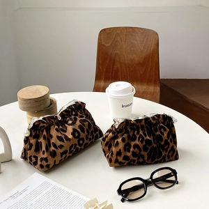 Portable leopard print plush makeup bag with pearl clasp on a white table setting