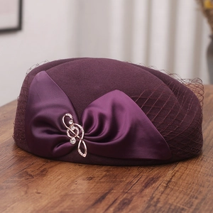 Detail of dark purple wool pillbox hat with satin bow, mesh veil and musical pin