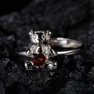 Macro shot of a 925 silver bear ring holding a heart-shaped red garnet on dark stone