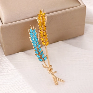Macro shot of rhinestone wheat ear brooch with blue and yellow gems on gold base