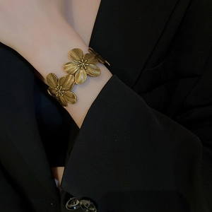 Detail view of vintage golden flower cuff bracelet with textured brushed metal finish