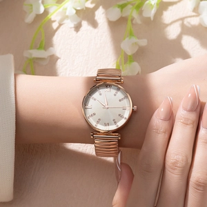 Detail of rose gold ladies watch with roman numeral dial and flexible expansion band