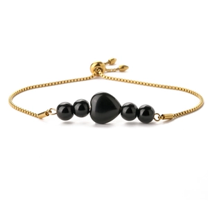 Detailed macro view of a 14K gold-plated heart bracelet with black beads and a slider clasp