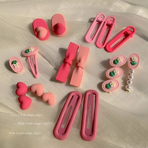 Pink hair clips set with matte bow, daisy and heart shapes on soft white fabric background