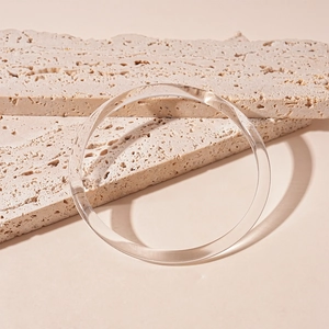 Vue détaillée du bracelet jonc en acrylique transparent sur fond de pierre beige