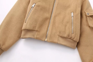 Detail of camel wool jacket featuring metal zipper ribbed hem and tactical sleeve pocket