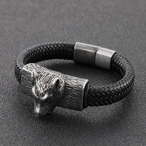 Close-up of antique silver wolf head charm on a black braided leather bracelet for men