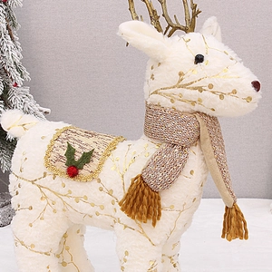 Dettaglio ravvicinato della decorazione di renna in peluche bianco con stampa dorata.