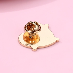Detailed view of the golden metal pin back with butterfly clutch fastener on pink background