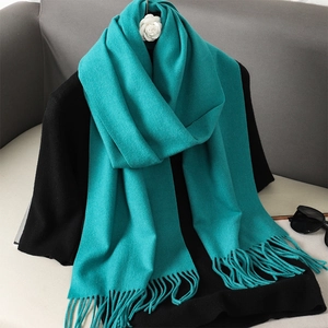 Detail of lake blue cashmere-feel scarf with tassel fringe on black clothing
