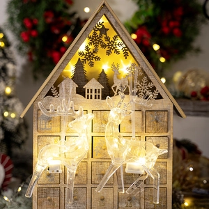 Close-up of LED glowing reindeer ornaments with a wooden Christmas advent calendar house