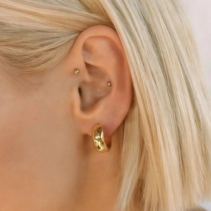 Detail of 14K gold plated chunky hoop earrings and stud set worn by a model