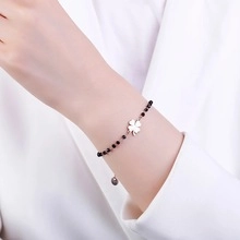 Detail of silver clover bracelet with black beads on wrist for a minimalist luxury look