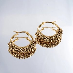 Detailed macro view of gold hoop earrings with beaded textures and high-polished finish