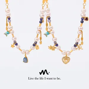 Close-up of pearl necklace with blue gemstones and gold heart and dragonfly charms