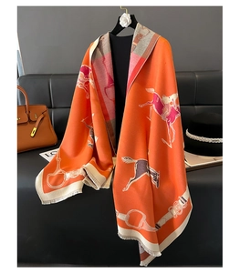Detail of orange equestrian scarf with horse pattern, tassels, and soft thick fabric