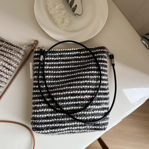 Close-up of black and white striped woven crossbody bag with long shoulder strap