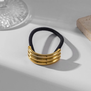 Close-up of black elastic hair tie with three-ring golden stainless steel hardware detail
