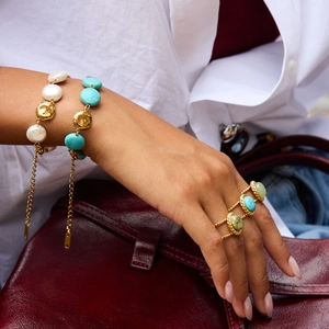 Close-up of golden turquoise beaded bracelets and gemstone ring on a model wrist