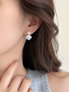 Detail of shell texture earring with white pearl on model showing elegant style