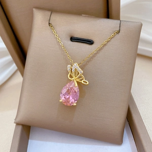 Macro detail of a gold butterfly necklace with pink teardrop crystal and pavé rhinestones