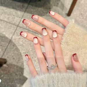 Detail of burgundy French cat-eye press-on nails with silver glitter and red tips
