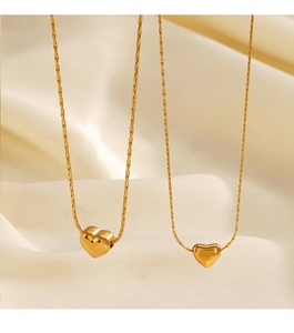 Détail de deux colliers à pendentif cœur plaqués or 18 carats sur tissu en soie beige
