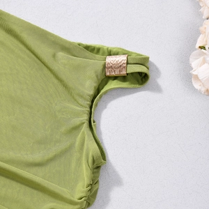 Détail du tissu froncé vert montrant les plis texturés et une boucle dorée