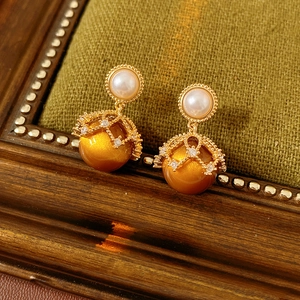 Vintage gold stud earrings with pearls and crystals on green velvet and wooden frame