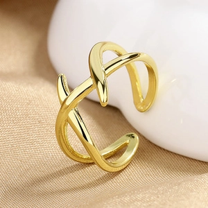 Close-up of golden geometric crossover ring on elegant silk fabric background