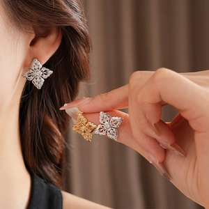 Detail of hollow flower stud earrings in gold and silver with zircon accents and filigree