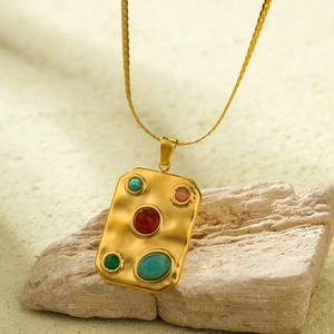 Macro view of gold rectangular textured pendant with five colorful natural gemstones